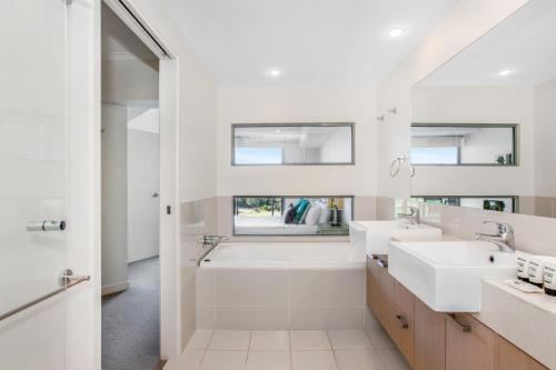 a white bathroom with two sinks and a bath tub at Lakeside Family Oasis with Pool, Gym and Balcony in Gold Coast