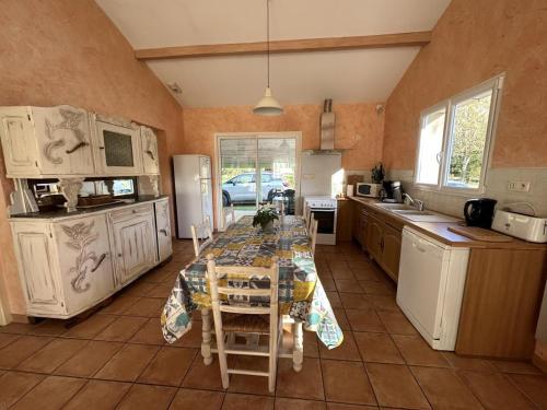 une cuisine avec une table avec des chaises et un réfrigérateur dans l'établissement Yaou, à Benquet