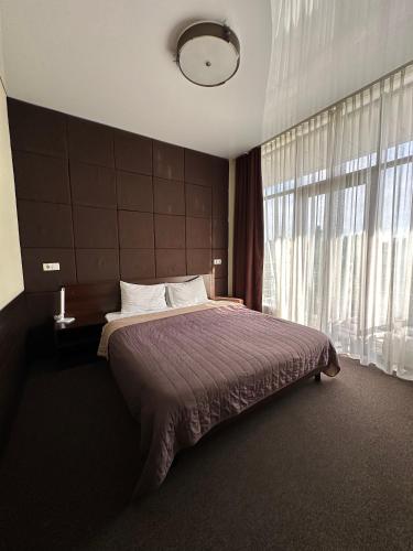 a bedroom with a bed and a large window at Hotel Atmosphere in Poltava