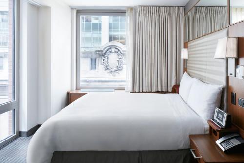 ein Schlafzimmer mit einem großen weißen Bett und einem Fenster in der Unterkunft Club Quarters Hotel Grand Central, New York in New York