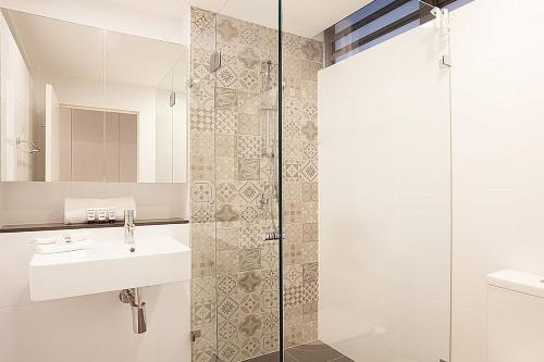 a bathroom with a sink and a glass shower at Stylish Studio with Balcony near Darling Square in Sydney
