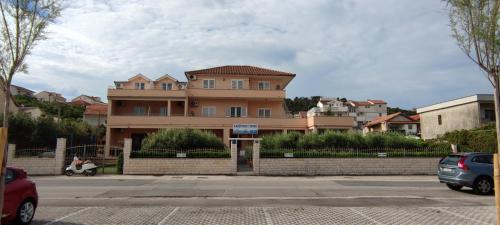 un grand bâtiment avec des voitures garées devant lui dans l'établissement Apartments Kapetanovi Dvori, à Trogir