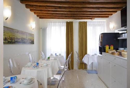 a dining room with white tables and chairs and a kitchen at Hotel Adriatico in Venice
