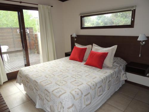 1 dormitorio con 1 cama grande y 2 almohadas rojas en Cabañas Klippen en Mar del Plata