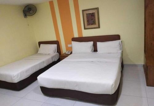 two beds in a hotel room with white sheets at Sun Inns Hotel Cheras - Balakong in Cheras
