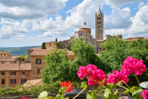 a view of a city with a clock tower and pink flowers at Carmelita in Massa Marittima