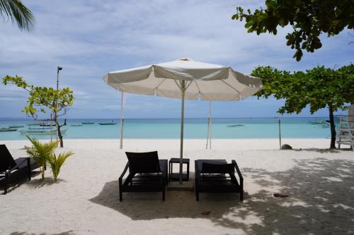 a table and chairs under an umbrella on the beach at Costa Liz Island Resort in Pooc
