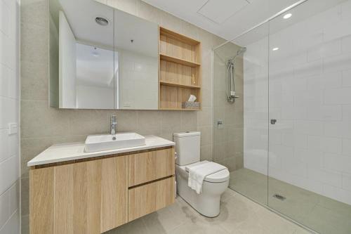y baño con aseo, lavabo y ducha. en Modern 1-Bed Apartment With Parking, Pool and Gym en Phillip