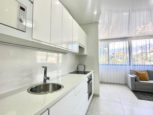 a white kitchen with a sink and a couch at Fantastic vacation by the ocean in Playa de las Americas