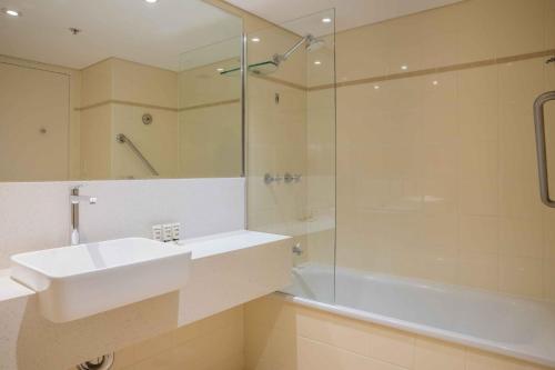 a bathroom with a sink and a shower and a tub at Central 1-Bed with Parking, Pool, Sauna & Gym in Sydney
