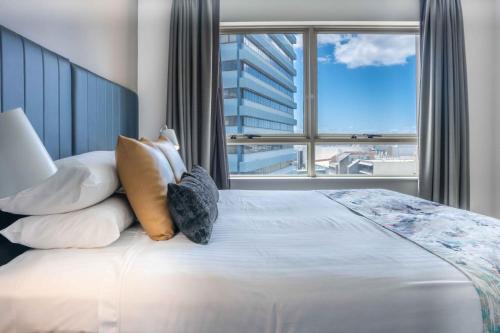 a bedroom with a large bed with a large window at Central 1-Bed with Parking, Pool, Sauna & Gym in Sydney