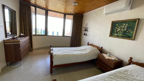 een slaapkamer met 2 bedden, een dressoir en ramen bij Abdoun Apartment in Amman