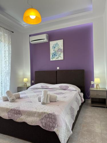 a bedroom with a large bed with purple walls at Savvas Apartment in Afantou