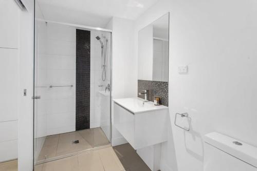 uma casa de banho branca com um lavatório e um chuveiro em Spacious 2-Bed Unit With Balcony Next to The Gabba em Brisbane