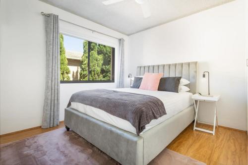 een witte slaapkamer met een groot bed en een raam bij Unit With Balcony, Backyard and Parking Near Shops in Sydney