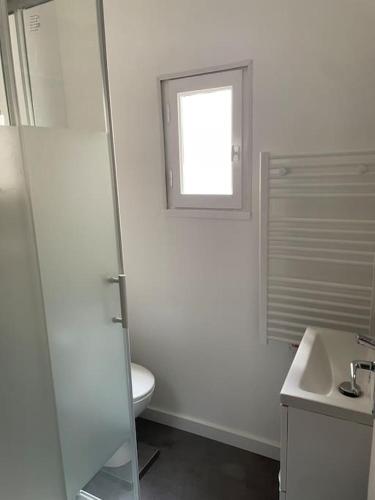 une salle de bain blanche avec toilettes et fenêtre dans l'établissement L'entre Stud', à Castres