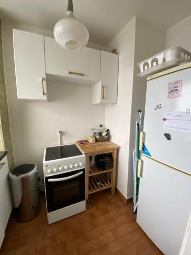 La cuisine est équipée d'une cuisinière blanche et d'un réfrigérateur. dans l'établissement Un pied-à-terre à Nogent-sur-marne, à Nogent-sur-Marne