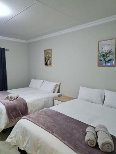 two beds in a room with white walls at Lukhanyo Guest House in Northam