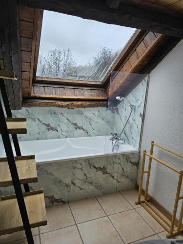 La salle de bains est pourvue d'une grande fenêtre et d'une baignoire. dans l'établissement Appartement Acolin, à Briançon