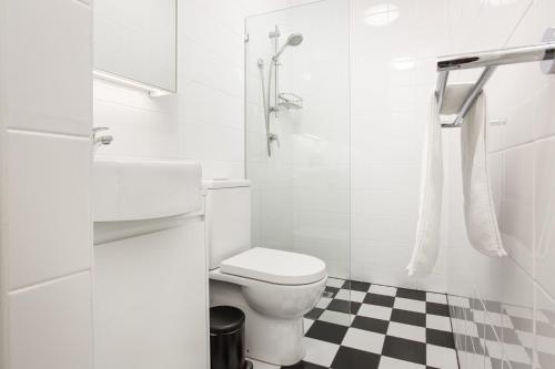 a white bathroom with a toilet and a checkered floor at Boutique Studio with Balcony in Perfect Location in Sydney