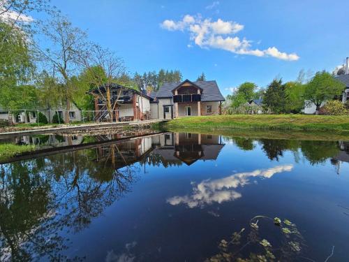 a house reflected in the water of a river at Pakalnės sodyba in Skverbai