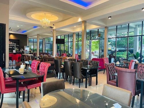 um restaurante com mesas, cadeiras e janelas em Pongsakorn Boutique Resort -SHA Extra Plus em Lat Krabang