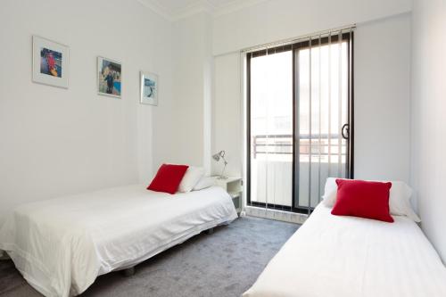 a white room with two beds and a large window at Chic Unit with Rooftop Terrace near Sights & Shops in Sydney