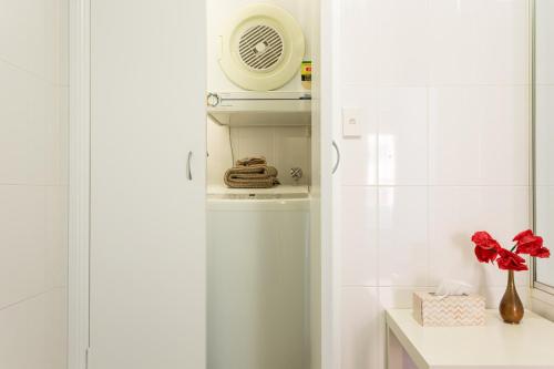 a white bathroom with a fan on a shelf at Chic Unit with Rooftop Terrace near Sights & Shops in Sydney