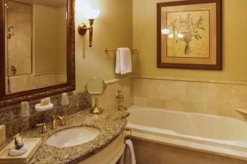 a bathroom with a tub and a sink and a mirror at Carlton Hotel in Atascadero