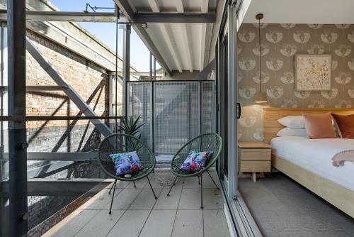 um quarto com 2 cadeiras e uma cama numa varanda em Designer 2-Bed Unit with Balcony Metres from Beach em Melbourne