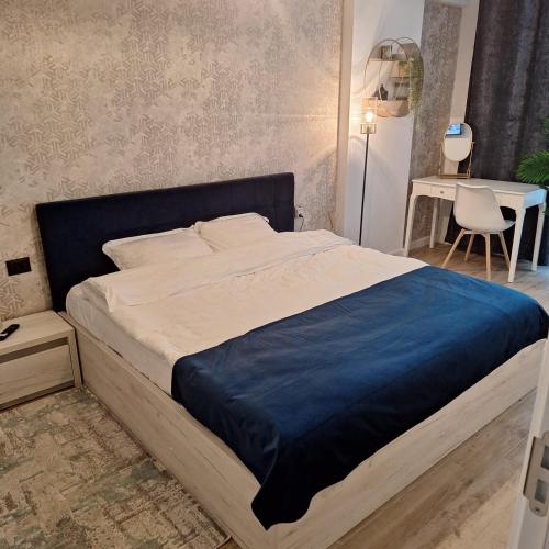 a bedroom with a large bed with a blue blanket at Nereide Apartament - Complex Infinity Pool in Mamaia Sat/Năvodari
