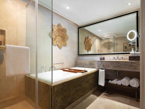 La salle de bains est pourvue d'une baignoire et d'une douche en verre. dans l'établissement InterContinental Bali Resort, an IHG Hotel, à Jimbaran