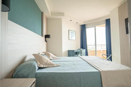 Un dormitorio con una cama grande con almohadas. en Aparthotel Dunes Platja en Can Picafort