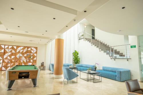 a living room with a pool table and blue couches at Aparthotel Dunes Platja in Can Picafort