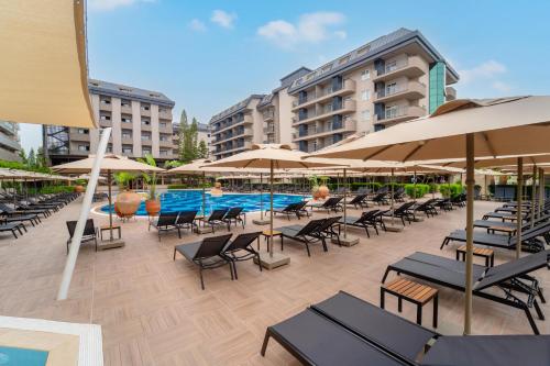 um pátio exterior com cadeiras e guarda-sóis e uma piscina em Villa Sunflower Beach Hotel - All Inclusive em Alanya