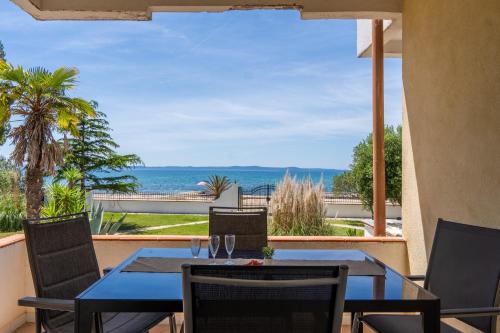 een patio met een tafel en stoelen en uitzicht op de oceaan bij Apartments Strand in Vir