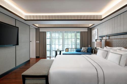een hotelkamer met een groot bed en een televisie bij Melia Koh Samui in Choeng Mon Beach