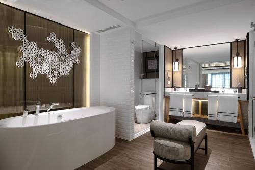 La salle de bains est pourvue d'une baignoire, d'une chaise et d'un lavabo. dans l'établissement Melia Koh Samui, à Choeng Mon Beach