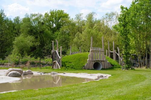 a playground in a park next to a body of water at Glamping Valkenburg in Meerssen