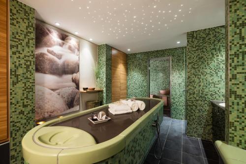 baño con bañera y ducha con azulejos verdes en Lindner Hotel Boltenhagen, part of JdV by Hyatt, en Boltenhagen
