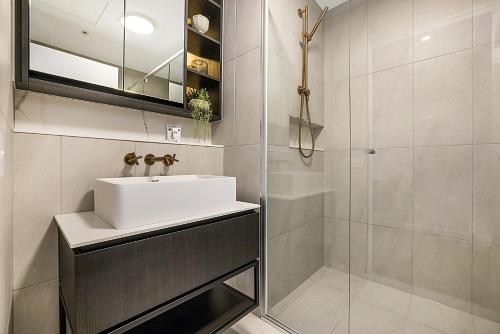 La salle de bains est pourvue d'un lavabo et d'une douche. dans l'établissement Modern, Executive 1 Bedroom Apartment With Balcony, à Melbourne