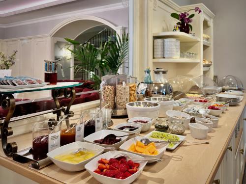 Windsor Merano Hotel & Suites في ميرانو: بوفيه مع العديد من أطباق الطعام على منضدة