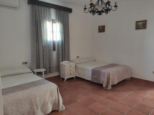 sypialnia z 2 łóżkami i żyrandolem w obiekcie Cortijo el Morisco. w mieście Espera