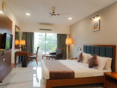 a bedroom with a large bed and a living room at Hotel Aditya in Raipur
