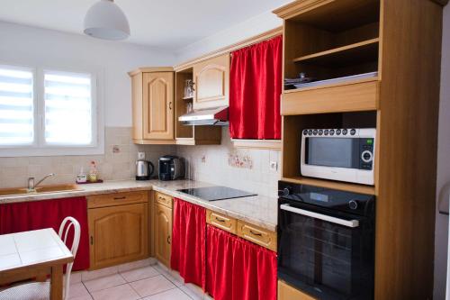 - une cuisine avec des placards en bois et des rideaux rouges dans l'établissement Family house with garden, à Saint-Hippolyte