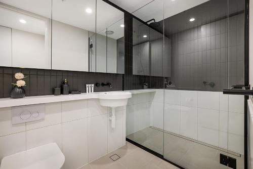 a white bathroom with a sink and a shower at Impeccably Styled 2-bedroom CBD Apartment in Melbourne