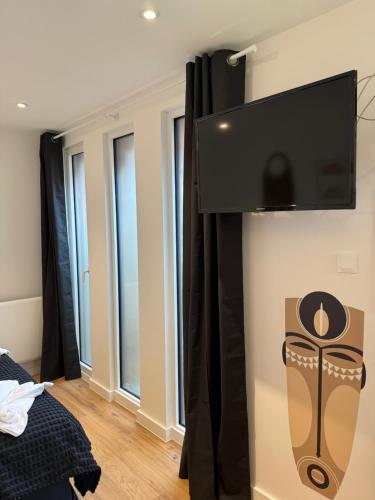 a flat screen tv hanging on a wall in a bedroom at Victorias House Suite in Lille