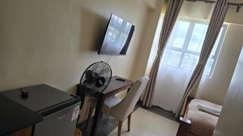 a room with a desk with a fan and a television at RCMRD EXECUTIVE SUITEs in Nairobi
