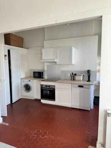 - une cuisine avec des placards blancs et un sol rouge dans l'établissement Appartement Marseille 13008 - 5min à pied Stade Vélodrome, à Marseille