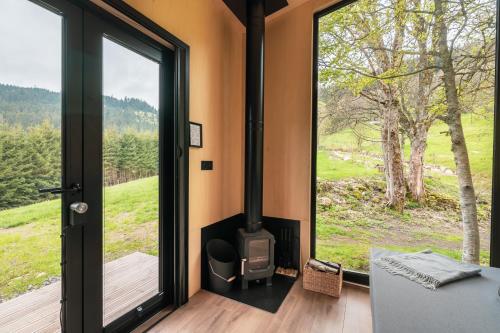 Habitación con chimenea y ventana con vistas. en cozy Black Forest Tiny House close to lake, en Schluchsee